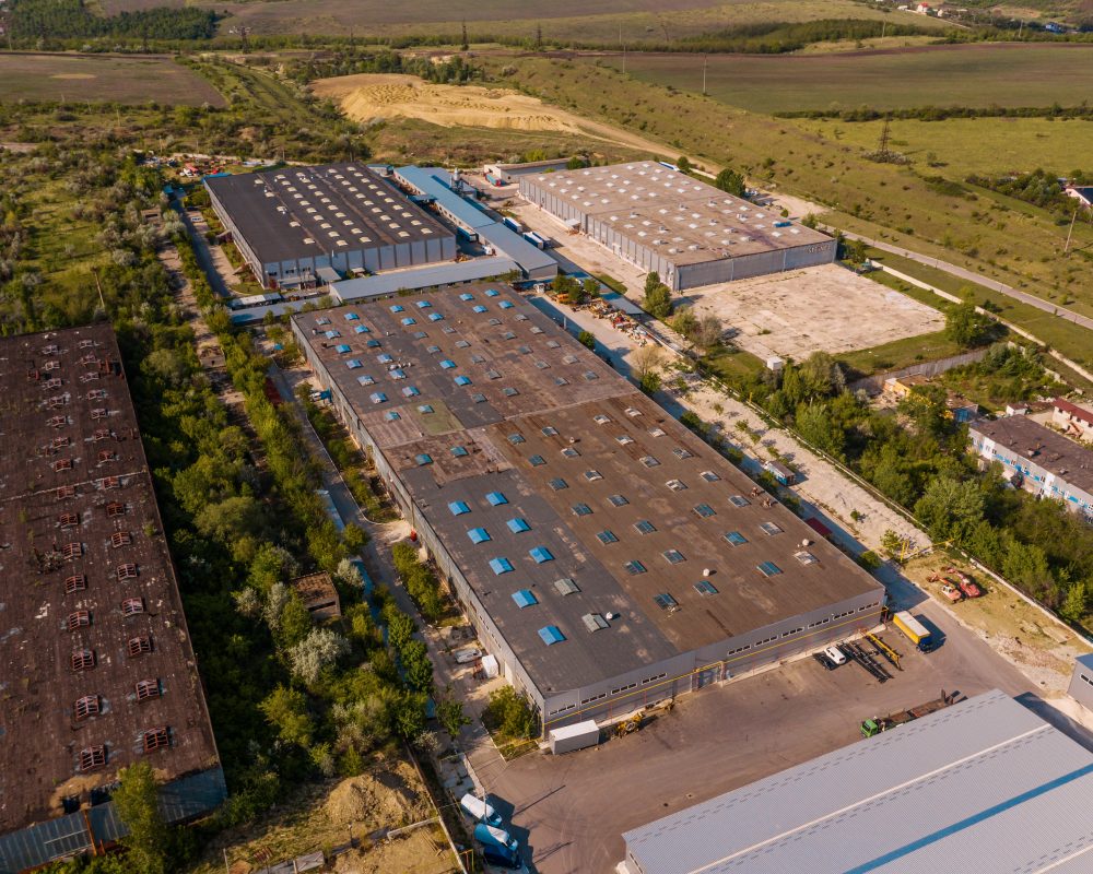 Aerial view of goods warehouse. Logistics center in industrial city zone from above. Aerial view of trucks loading at logistic center in agreen zone